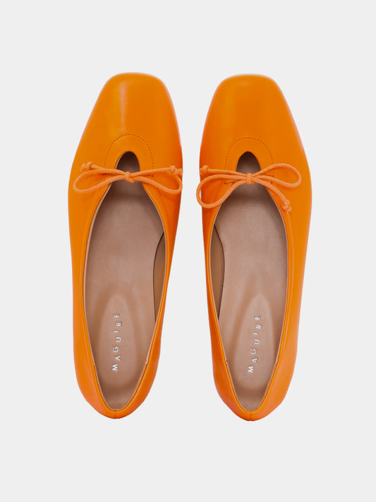 Pair of orange flats with matching laces on a light gray background