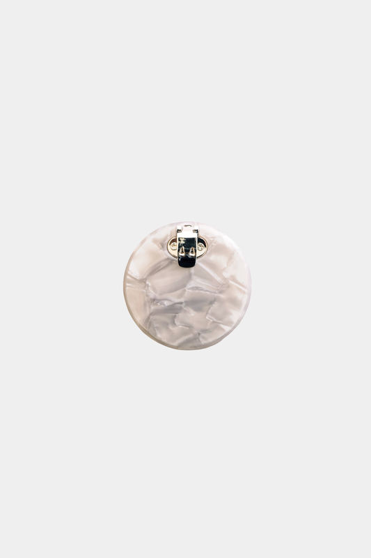 Ecom image of a round acetate shoe clip, cream coloured, back clasp.