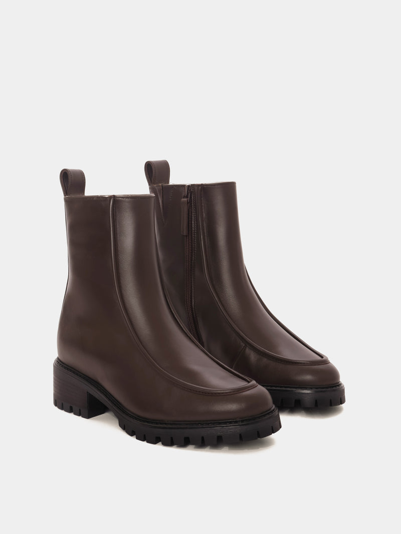 Shearling lined winter boot with a front piping detail, in a dark brown leather with a black lug outsole. 