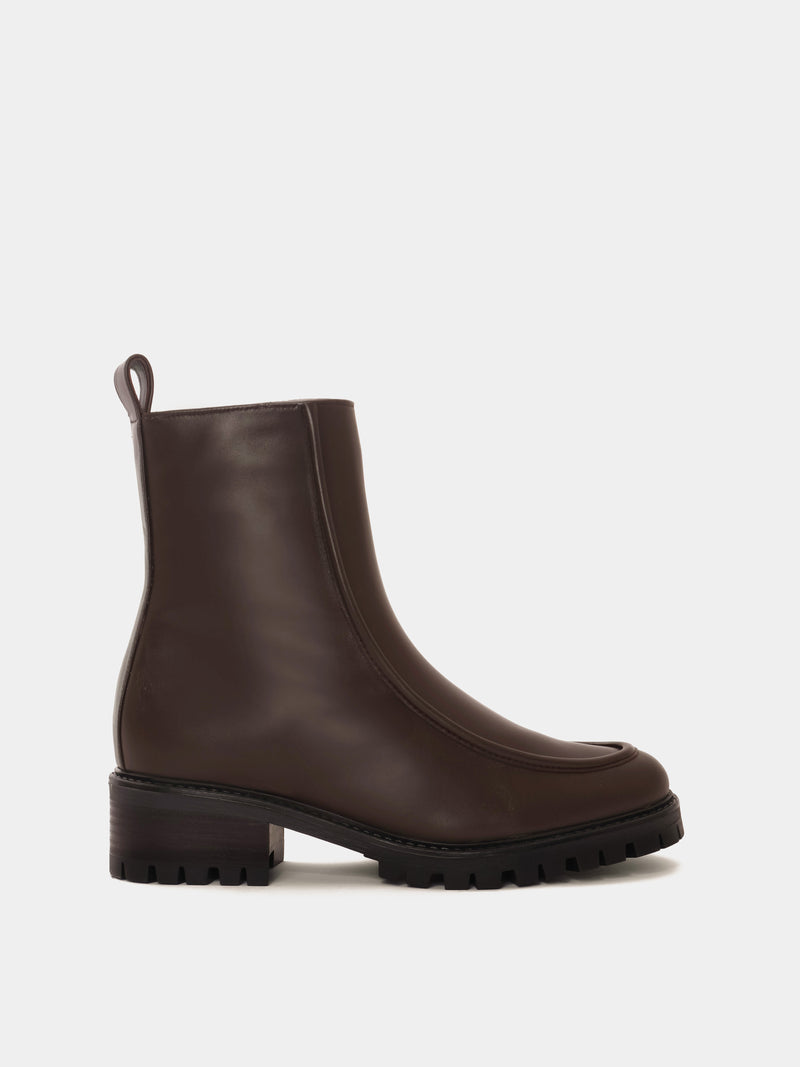 Shearling lined winter boot with a front piping detail, in a dark brown leather with a black lug outsole. 