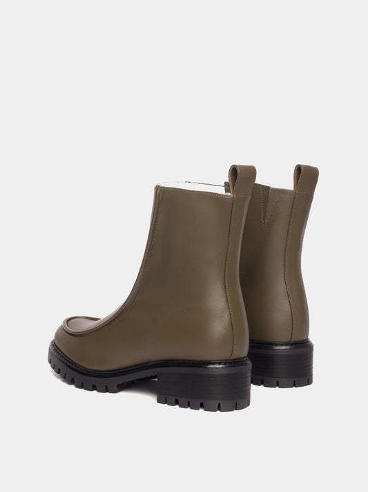 Shearling lined winter boot with a front piping detail, in an olive green leather with a black lug outsole. 