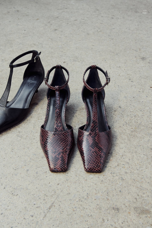 Pair of snakeskin-patterned high-heeled shoes on a concrete surface